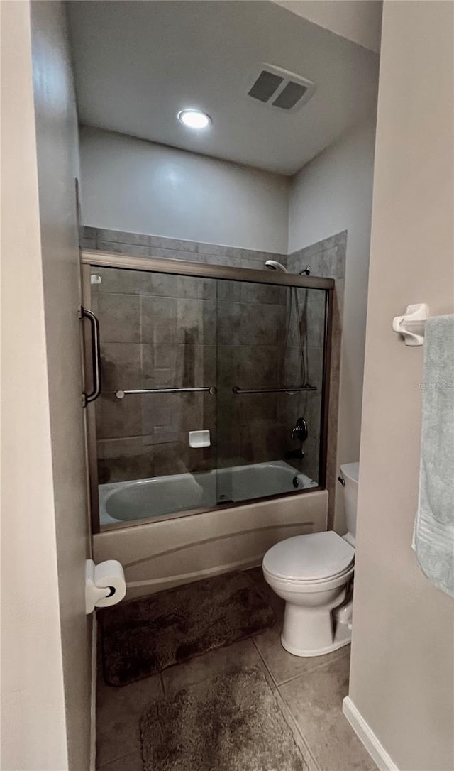 bathroom with tile patterned flooring, toilet, and bath / shower combo with glass door