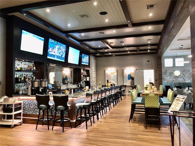 bar with beamed ceiling and light hardwood / wood-style floors