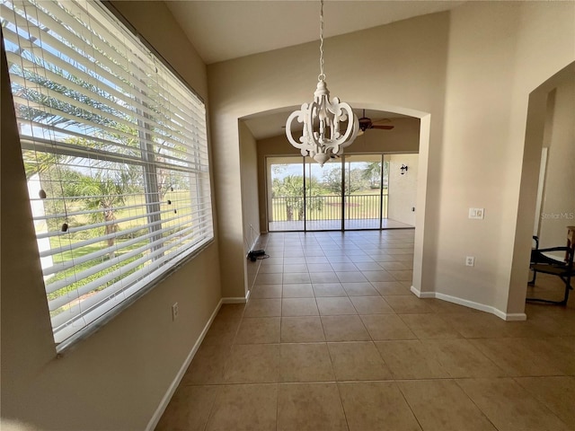 unfurnished dining area with light tile patterned floors and ceiling fan with notable chandelier