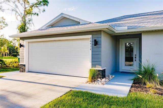 view of front of property with an attached garage, stucco siding, and roof with shingles