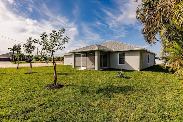 rear view of house with a yard and a sunroom