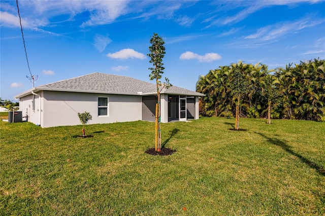 rear view of property featuring a sunroom, a lawn, and stucco siding