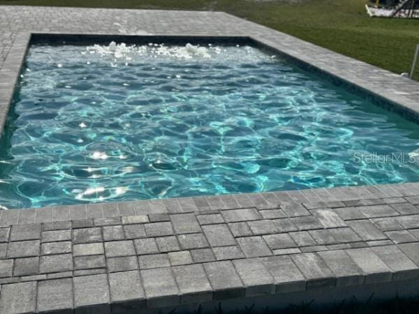 view of swimming pool featuring a jacuzzi and a lawn