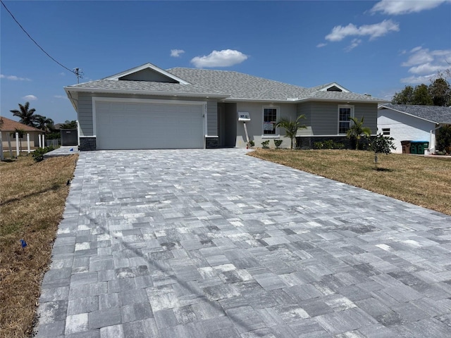 ranch-style house featuring an attached garage, a front yard, and decorative driveway