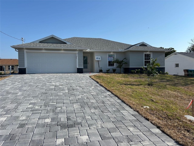 ranch-style house with decorative driveway, a front yard, and a garage