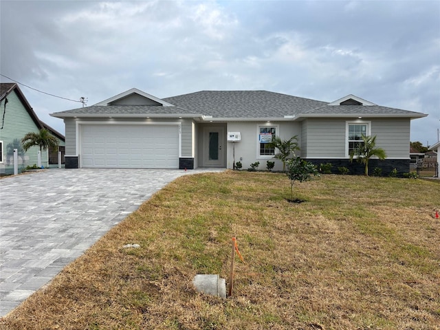 ranch-style home with an attached garage, a front lawn, decorative driveway, and roof with shingles