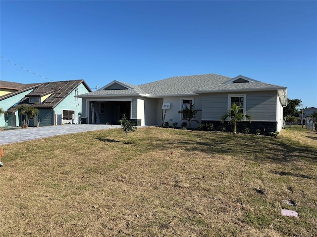 view of front of house featuring an attached garage, a front lawn, roof with shingles, and decorative driveway