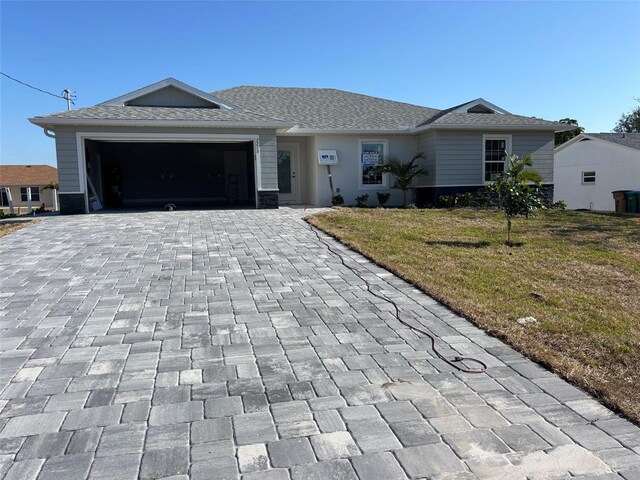 single story home with a front lawn, decorative driveway, and an attached garage