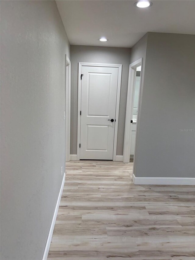 hall featuring recessed lighting, baseboards, and light wood-type flooring