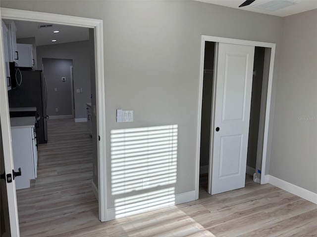 interior space with visible vents, baseboards, light wood-style floors, and a closet