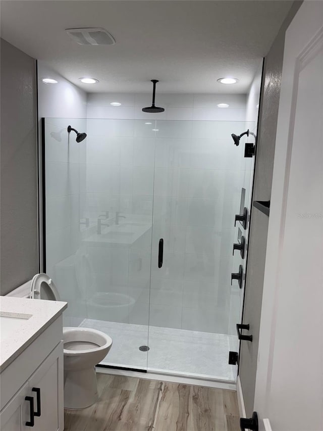 bathroom with toilet, a stall shower, visible vents, wood finished floors, and vanity