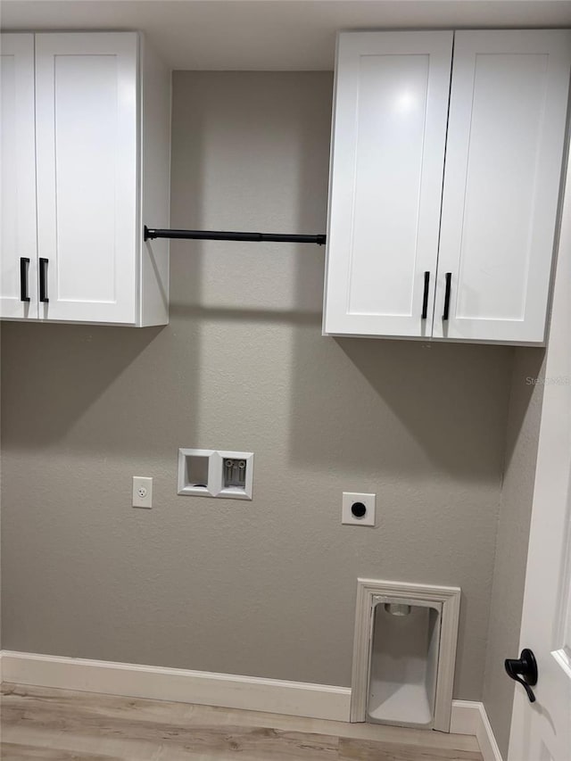 clothes washing area with hookup for an electric dryer, cabinet space, light wood-style flooring, baseboards, and washer hookup