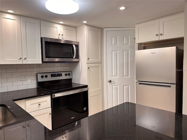 kitchen featuring appliances with stainless steel finishes, decorative backsplash, white cabinetry, and dark stone counters