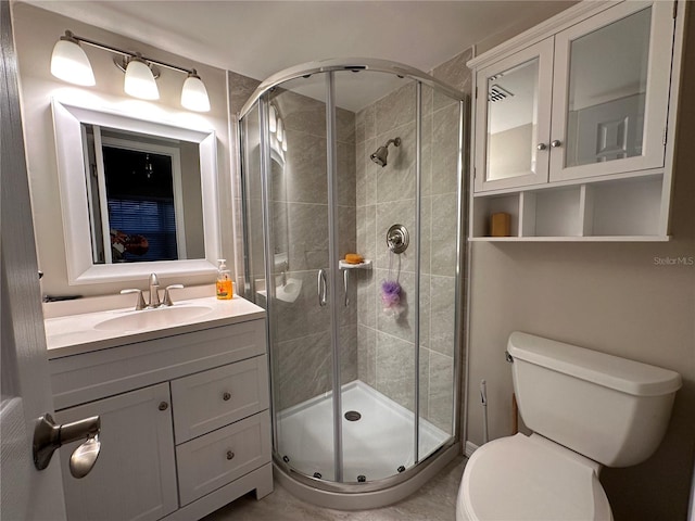 bathroom featuring toilet, vanity, and a shower with shower door