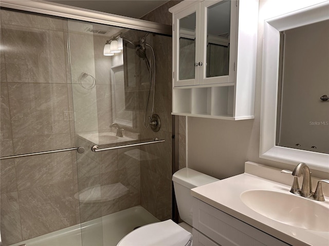 bathroom featuring a shower with door, toilet, and vanity