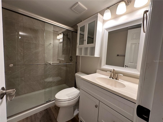 bathroom with a shower with shower door, toilet, hardwood / wood-style floors, and vanity