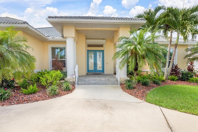 property entrance featuring french doors, a tile roof, and stucco siding