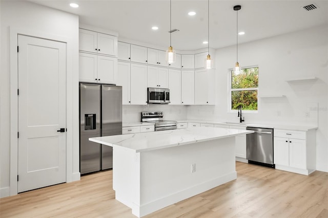 kitchen with light wood-type flooring, white cabinetry, a kitchen island, and appliances with stainless steel finishes