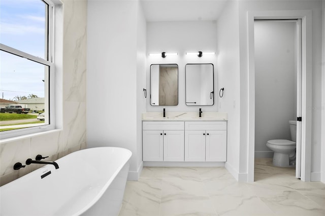 bathroom with a tub to relax in, vanity, and toilet