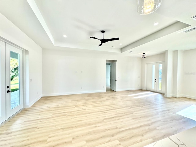 spare room with ceiling fan, a tray ceiling, french doors, and light hardwood / wood-style floors