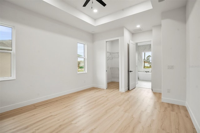 unfurnished bedroom featuring multiple windows, a spacious closet, and ceiling fan