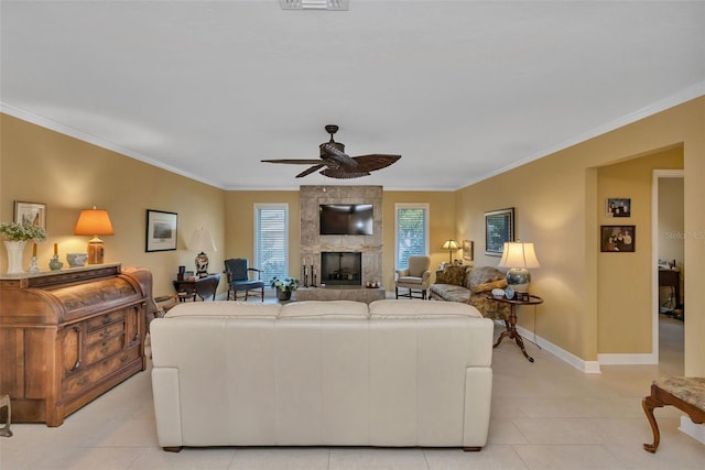 living room with a stone fireplace, ceiling fan, ornamental molding, and light tile patterned flooring