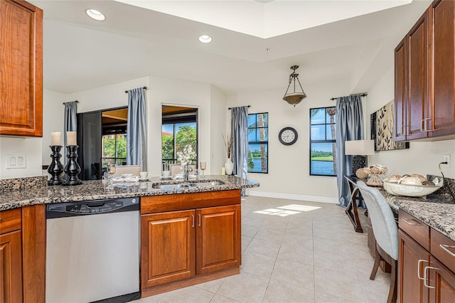 kitchen with sink, stainless steel dishwasher, dark stone counters, pendant lighting, and light tile patterned flooring