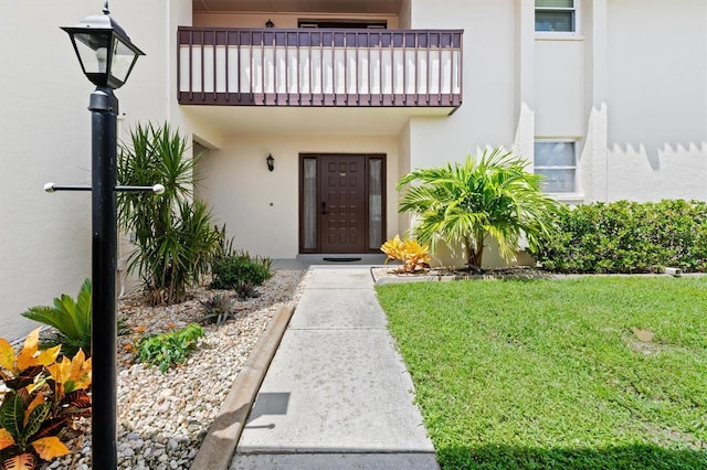 doorway to property featuring a lawn and a balcony