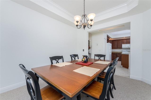 carpeted dining space with a tray ceiling, ornamental molding, and an inviting chandelier