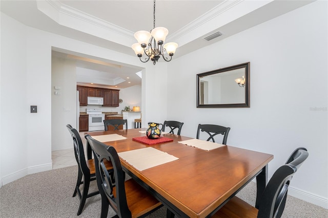 carpeted dining space featuring a raised ceiling, ornamental molding, and an inviting chandelier