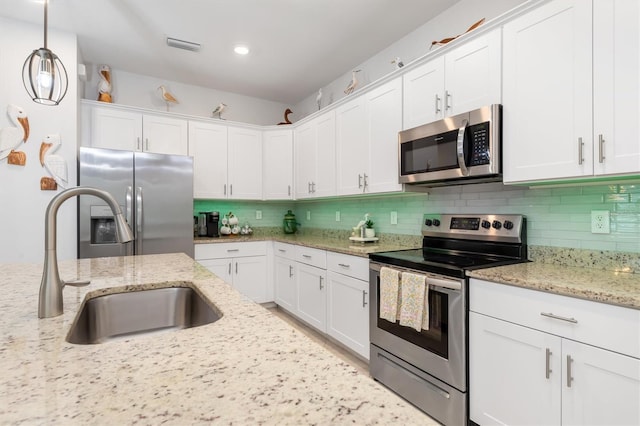 kitchen with backsplash, stainless steel appliances, white cabinetry, sink, and pendant lighting