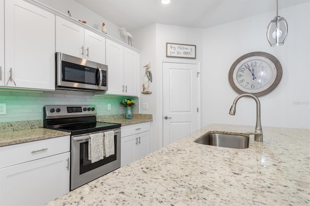 kitchen with stainless steel appliances, sink, light stone countertops, and white cabinets