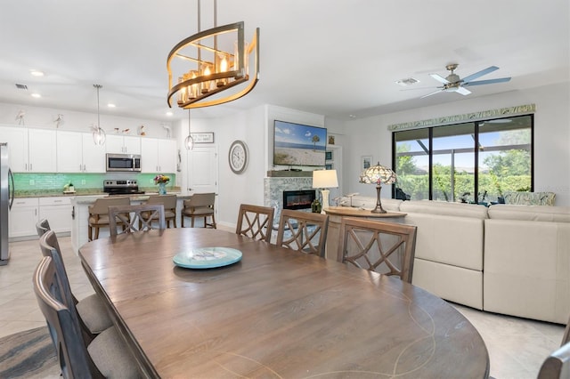 tiled dining room with ceiling fan with notable chandelier