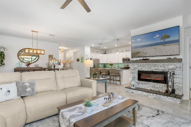 tiled living room with ceiling fan and a fireplace