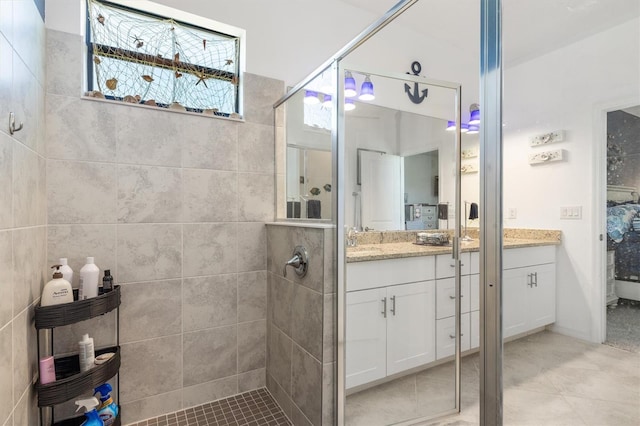 bathroom with tiled shower, vanity, tile walls, and tile patterned floors