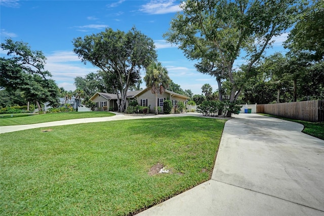 exterior space featuring fence, driveway, and a front lawn