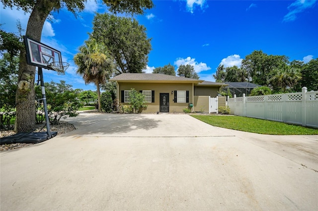 view of front of house with fence, concrete driveway, and a front yard