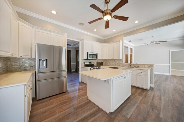 kitchen featuring appliances with stainless steel finishes, white cabinetry, hardwood / wood-style flooring, and tasteful backsplash