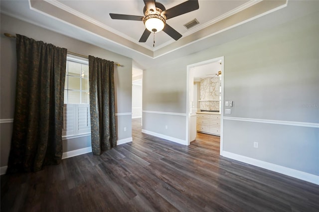 spare room featuring dark wood-style floors, a tray ceiling, visible vents, and baseboards