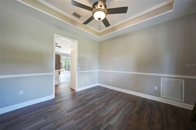 spare room featuring dark wood-style floors, a raised ceiling, visible vents, and baseboards