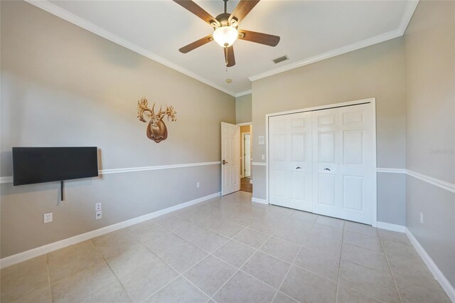 unfurnished bedroom with ceiling fan, a closet, light tile patterned flooring, and ornamental molding