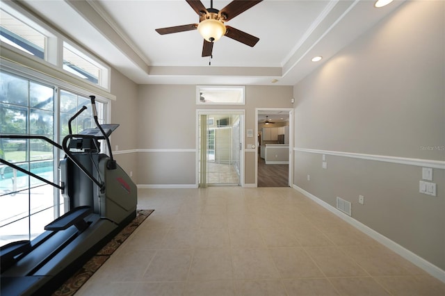 exercise area with ceiling fan, a tray ceiling, visible vents, and baseboards