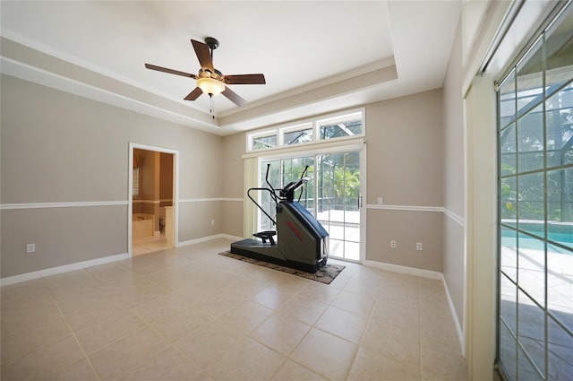 workout area featuring ceiling fan, a raised ceiling, and light tile patterned floors