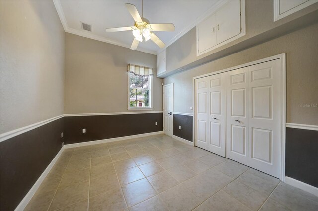 unfurnished bedroom with ceiling fan, ornamental molding, a closet, and light tile patterned floors