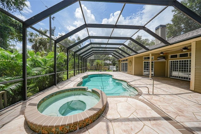 view of pool featuring glass enclosure, ceiling fan, a pool with connected hot tub, and a patio