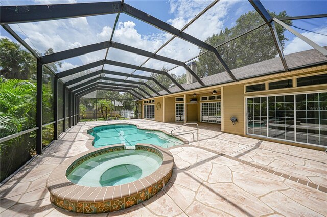 view of swimming pool featuring ceiling fan, a lanai, an in ground hot tub, and a patio area