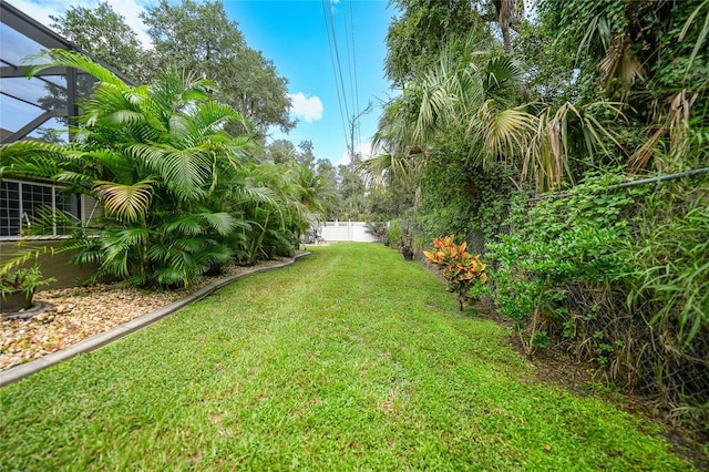 view of yard featuring glass enclosure and fence