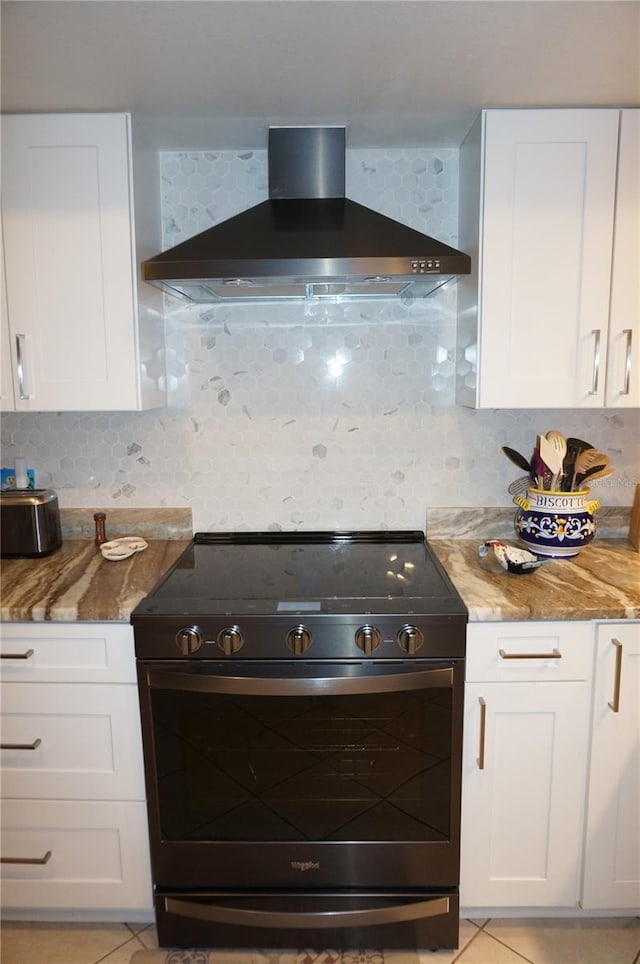 kitchen featuring stainless steel range, wall chimney range hood, white cabinets, and tasteful backsplash