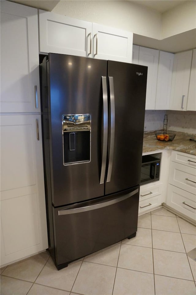 kitchen featuring black microwave, white cabinetry, light tile patterned floors, and stainless steel fridge with ice dispenser