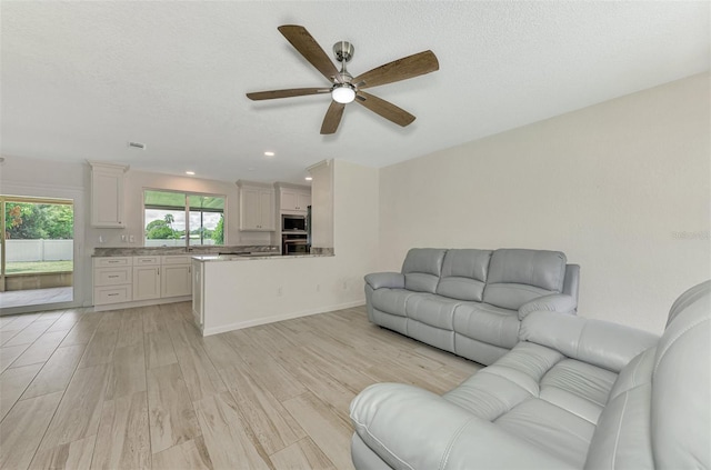 unfurnished living room with a textured ceiling, recessed lighting, a ceiling fan, baseboards, and light wood finished floors